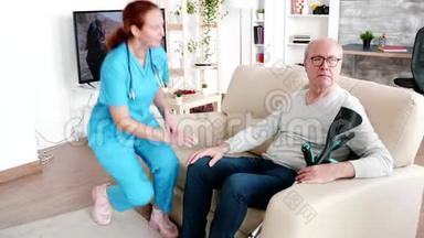 一位坐在养老院沙发上照顾老年痴呆症<strong>患者</strong>的女<strong>护士</strong>